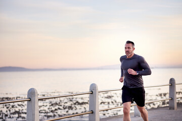 Ocean, running and man with energy, cardio and wellness with workout, exercise and routine. Person, athlete and runner with endurance, morning and fitness with body health, challenge and training