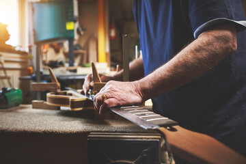 Handyman, worker or employee building a guitar, fixing an instrument and doing repair job at a workshop. Closeup of hands making, designing and creating a musical tool at a factory, shop or warehouse