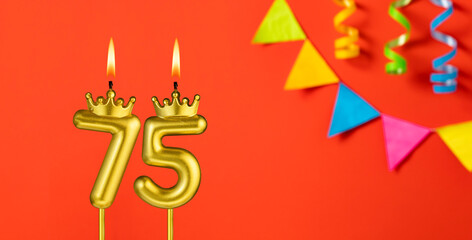Number 75 candle - Birthday celebration on an orange background with pennants