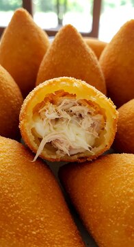 Crispy teardrop-shaped coxinhas filled with shredded chicken and catupiry cheese, golden fried crust, served on a banana leaf.