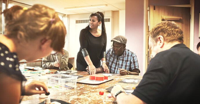 Disabled people with learning disability at community healthcare institution event, gather to learn art and tools to live a healthy life. Woman smiling teaching gives hope, motivation and inspiration