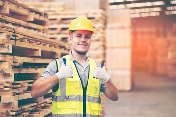 male worker or engineer showing thumbs up in wood. warehouse. Concept of smart industry worker operating. Wood factories produce wood furniture. 