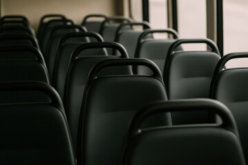 Fototapeta premium Empty bus interior with rows of black seats in soft light