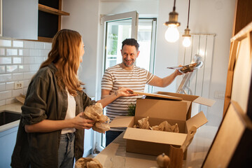 Couple unpacking boxes together in new home kitchen