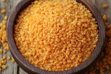 Close-up of vibrant yellow lentils in a wooden bowl on a rustic table, showcasing texture