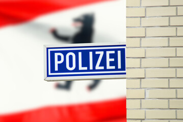 Schild einer Polizeiwache und Flagge mit Berliner Wappen im Hintergrund
