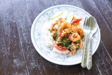 Shrimp Pad Krapow Rice placed on a white plate on a wooden table.