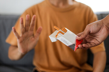 Man refusing a cigarette from a pack of smokes. Concept for quitting smoking and healthy lifestyle.