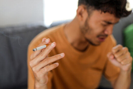 Man having a severe cough while smoking a cigarette at home