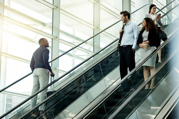 People, escalator and suitcase in airport for travel, international journey or passing friends. Immigration, travelers or luggage on electric stairs for business trip with flight schedule in terminal