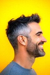 Obraz premium Artwork of style for aging men. Modish men's low fade haircut - midlife white man with black hair. Yellow solid background. A handsome man in his 40s with a radiant smile.