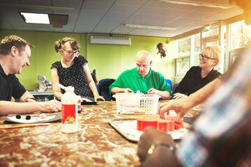 People at table, with down syndrome man, happy learning and therapy, to make cookies for mental...
