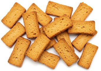A scattered pile of golden brown rectangular rusk bread slices on a plain white background surface top view