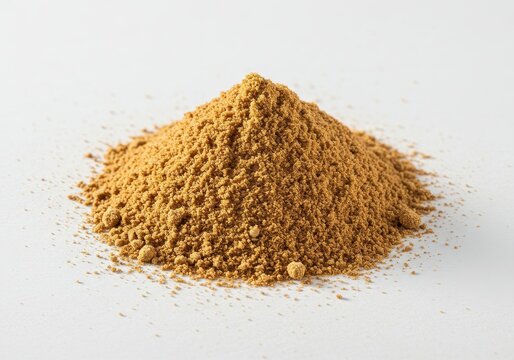 A mound of brown powder resting on a white surface with some scattered grains around the base area