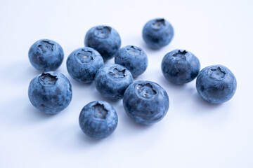 A cluster of blueberries, sits on a soft white surface, emphasizing freshness and texture.