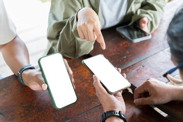 Hands of male and female friends using mobile phones on table in coffee shop.