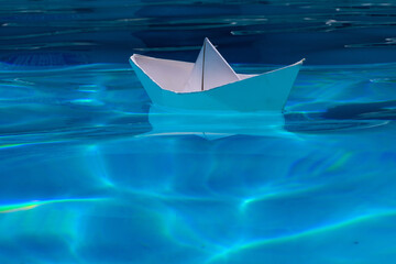 Fototapeta premium Paper boat on the sea background. Tourism, travel dreams vacation holiday. Cruise ship concept. Origami paper sailing boat. Paper craft and origami.