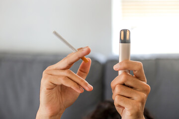 Man holding a cigarette and e-cigarette vaping device. Quitting smoke concept.