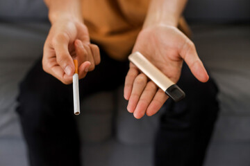 Vaping device and cigarettes in the man's hand, concept of choosing the type of cigarette