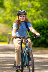 Fototapeta premium Child bike ride. Teen boy biking down summer road. Kid riding bicycle with smile. Child cycling. Kid ride on bike. Happy boy on bike. Child biking outdoors. Children biking. Little biker.
