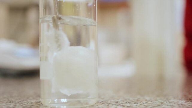 Paper cut was thrown into a flask of water and dissolved by stirring . Close-up