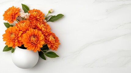 A vibrant bouquet of orange dahlias in a simple white vase rests on a clean marble surface providing ample copy space for text or design elements.