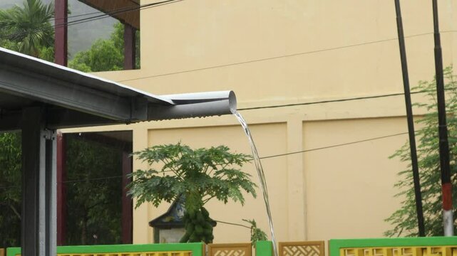 water flowing from the pipe on the roof of the house