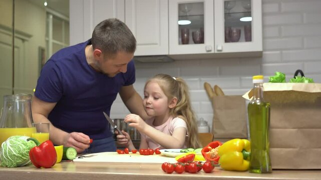Father and daughter cooking activity: family fun in the kitchen with fresh vegetables.