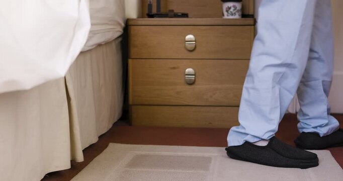 Senior man, bed and shoes for walk, start and morning in home in pajamas on carpet in retirement. Elderly gentleman, comfort and orthopedic slippers for easy walking in bedroom, apartment and house