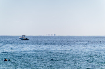 Calm blue sea with the silhouette of a large ship on the horizon
