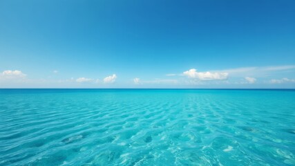 Fototapeta premium A tranquil turquoise ocean scene showcases a calm sea under a vibrant blue sky with fluffy white clouds peacefully floating above.