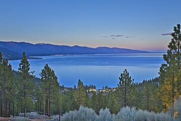 Scenic lake vista at dawn Mountain range and pine forest edge the tranquil water