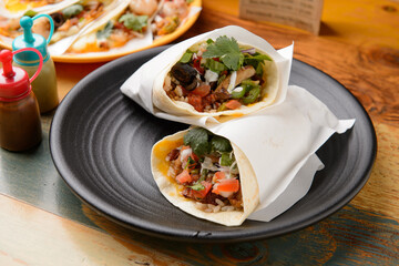 There's a burrito on a black plate.
