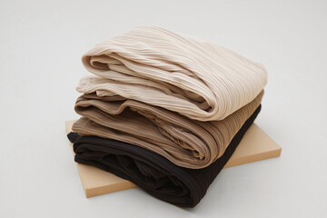 Premium hornet knit fabric texture in brown, cream pastel and black colors. Premium hornet fabric stacked upwards on white background. Close up, studio shot. Used for woman and child fashion.