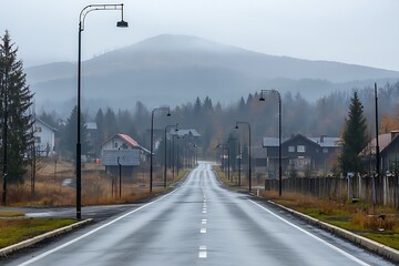 Rainy Asphalt Road Through Rural Town With Mountain Views and Foggy Haze Landscape