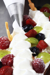 piping cream to a cake with fruit topping