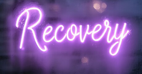 Bright purple neon sign displays word recovery. Dark background creates strong contrast, emphasizing message. Simple, bold lettering.