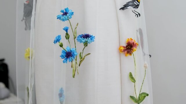 Beautiful embroidery flowers on cotton fabric. Product of needlework on a piece of embroidery. Needlework is decorative sewing and textile arts handicrafts. How to stitch embroider flowers on clothes.