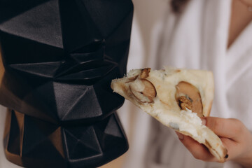 Close-Up of Artistic Sculpture and Gourmet Flatbread Pizza Slice in Hand
