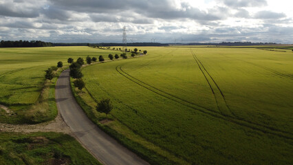 Fototapeta premium Aerial view of small rural winding road with single cyclist in distance