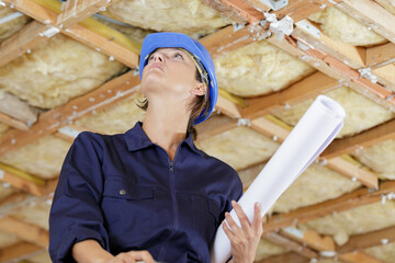 woman builder engineer in helmet looking at blueprint paper