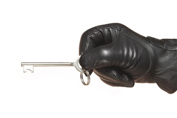 A man's hand in a black leather glove holds a key in a horizontal position. Isolate on white.