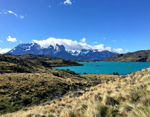 A panoramic view of the Torres del Paine National Park featuring glacier-fed lakes, jagged peaks, and endless grasslands.