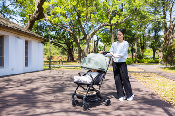 Mum walking with baby son in stroller at park