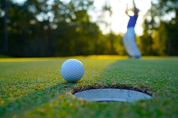 Golfer playing golf in the evening golf course, on sun set evening time.
