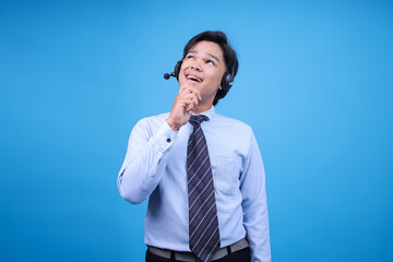 Young call center man wearing headset with hand on chin thinking about question, pensive expression.
