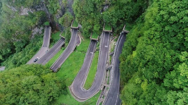 Historic cliffside road twists dramatically through tunnel hairpin bends, Italy