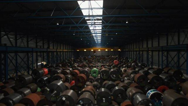 Dynamic overhead view of large steel coils packed in a dark warehouse