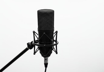 A black microphone with a pop filter on a stand against a white background in studio setting view