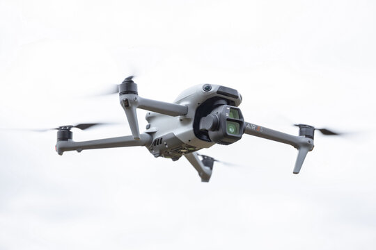 Rotmanka, Poland - April 24, 2025: Drone DJI Air 3S with the two lens gimbal flying over white background.